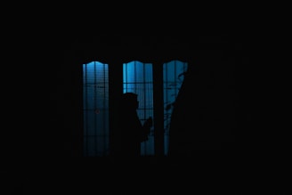 a person standing in front of a window in the dark