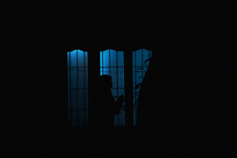 a person standing in front of a window in the dark