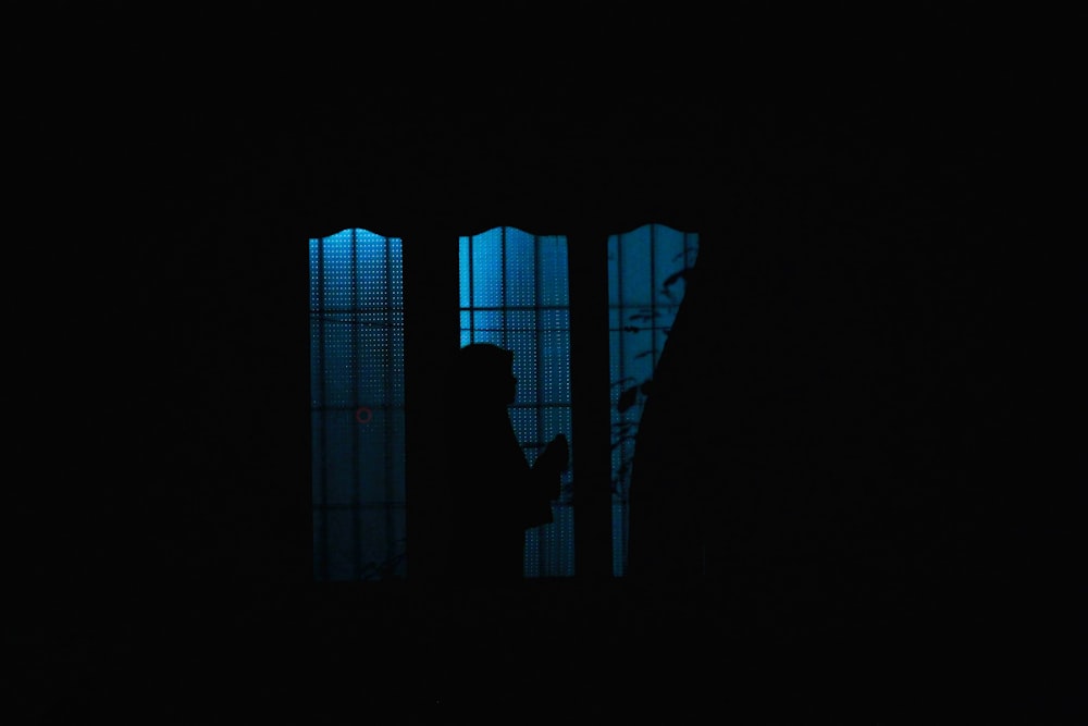 어둠 속에서 창문 앞에 서있는 사람