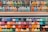 A variety of colorful markers arranged neatly on shelves. The markers are sorted by hues and tones, ranging from bright pinks, oranges, and reds to cool blues, greens, and purples. Each row displays a different gradient of shades.