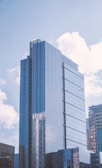 A modern skyscraper reflecting the sky in a bustling city