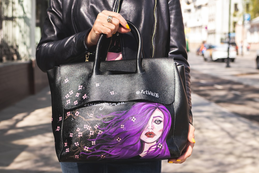 person holding black leather bag