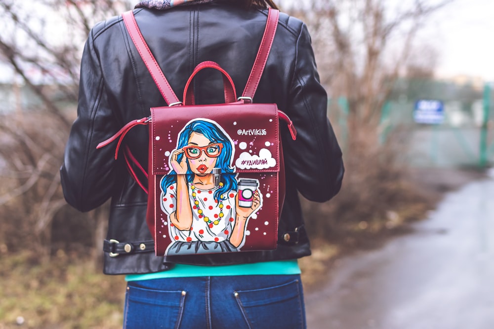 woman in black jacket and blue denim jeans with brown leather backpack