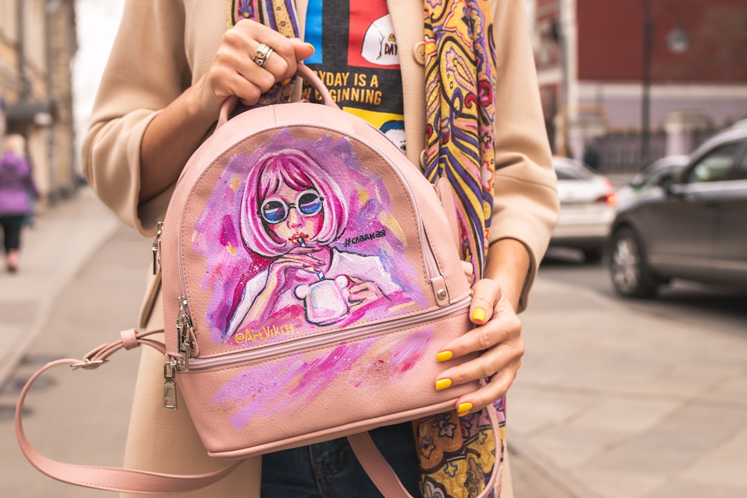 woman carrying pink painted brown leather backpack