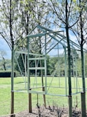 Metal structure of an A-Frame kit standing in a lush green forest clearing, ready for assembly.