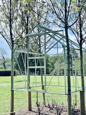 Metal structure of an A-Frame kit standing in a lush green forest clearing, ready for assembly.