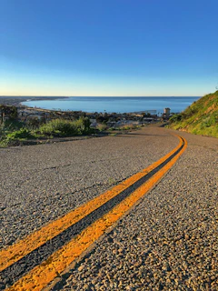 gray concrete road viewing blue sea under blue and white skies