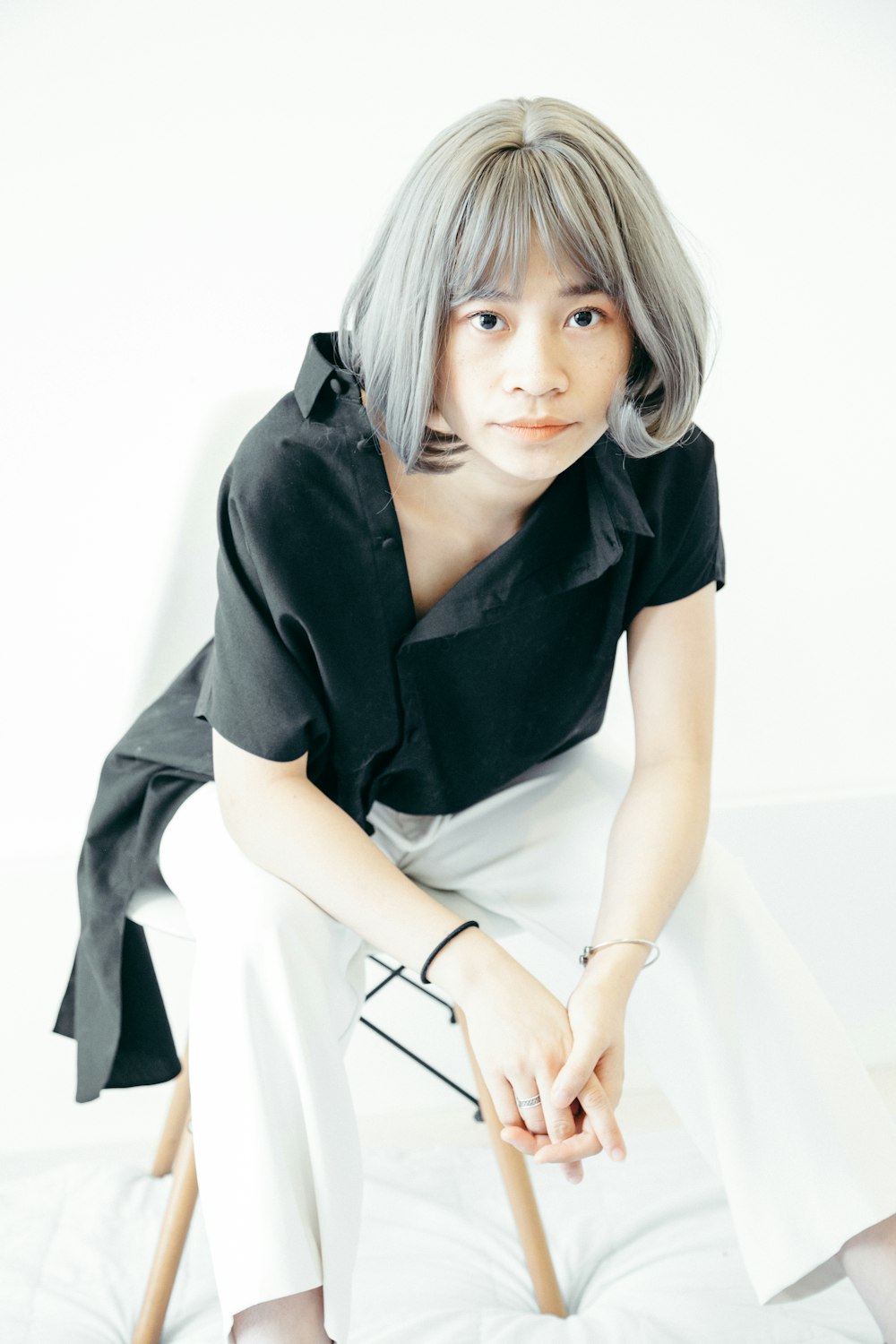 woman in black button-up short sleeved shirt and white pants sitting on chair