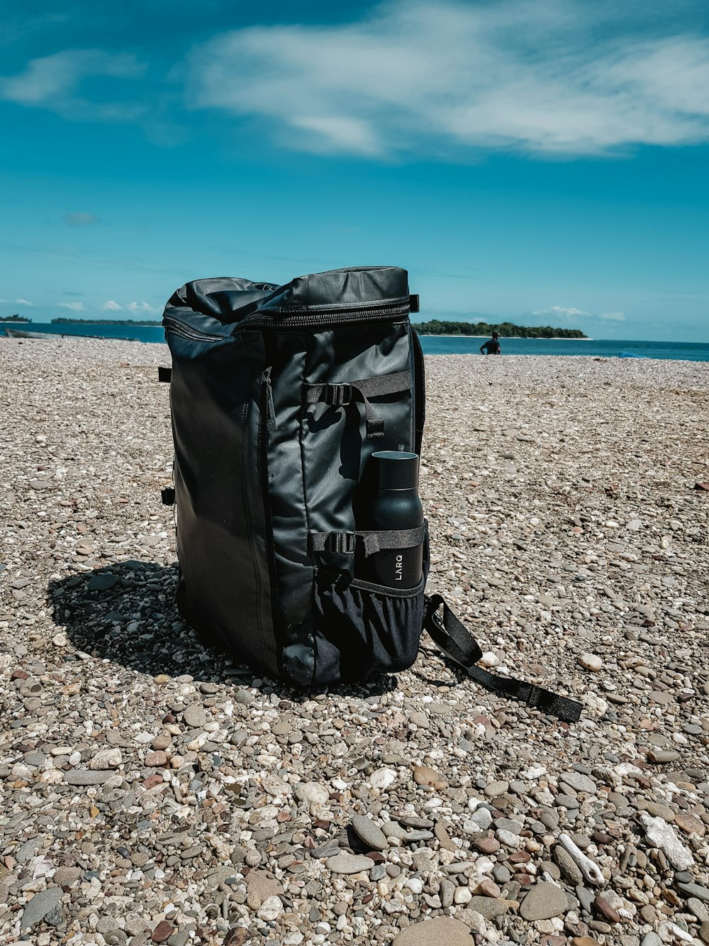 black leather bag on brown rocky beach