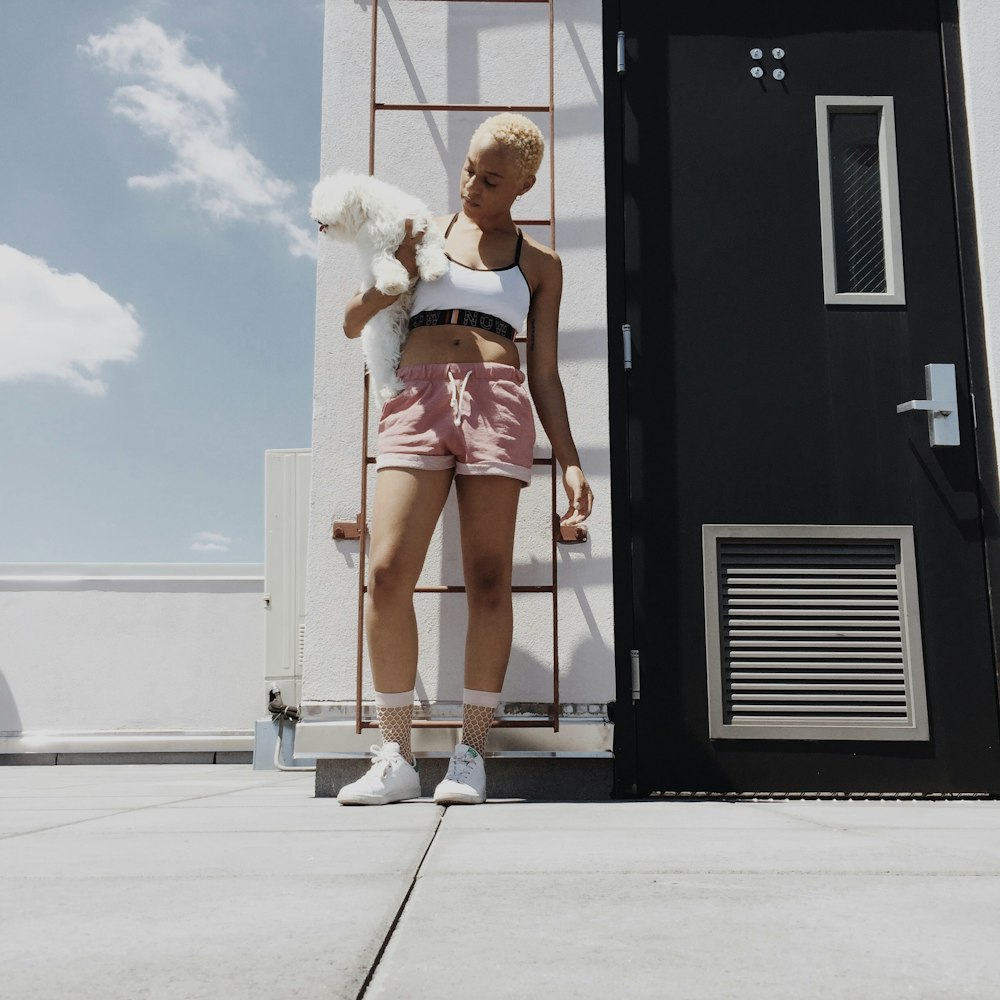 woman holds long-coated puppy at the top of the building