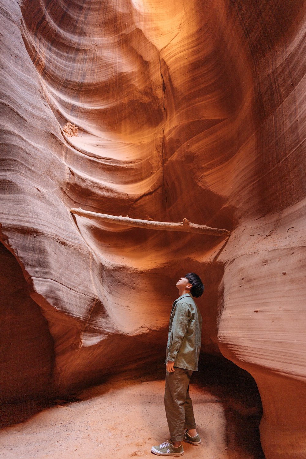 man standing inside brown rock cave