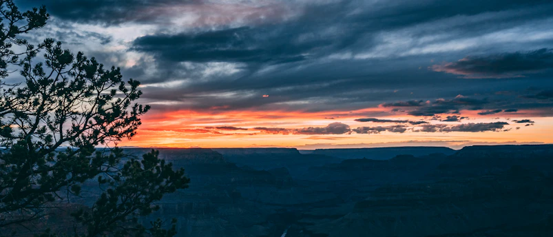 Sunset over Kanab's red rock cliffs with a cozy cabin in the foreground.