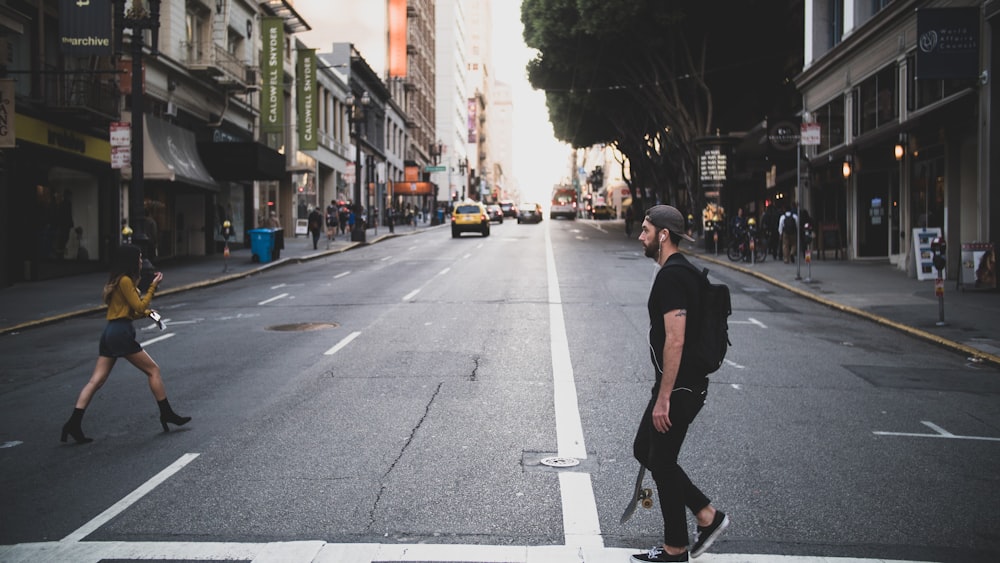 man wearing black shirt crossing on road