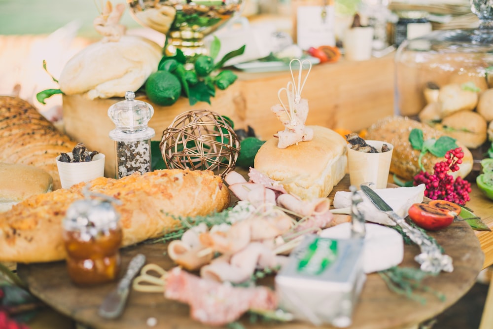 assorted deli cuts and bread on a brown wooden tray