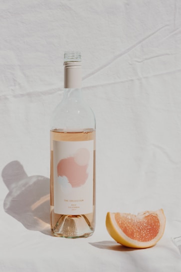 A chilled bottle of rosé wine resting on a rustic wooden table with soft natural light highlighting its pink hue.