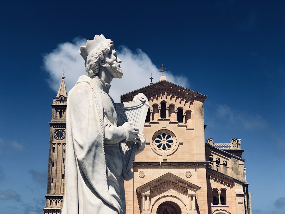 man with harp statue in front of the church building