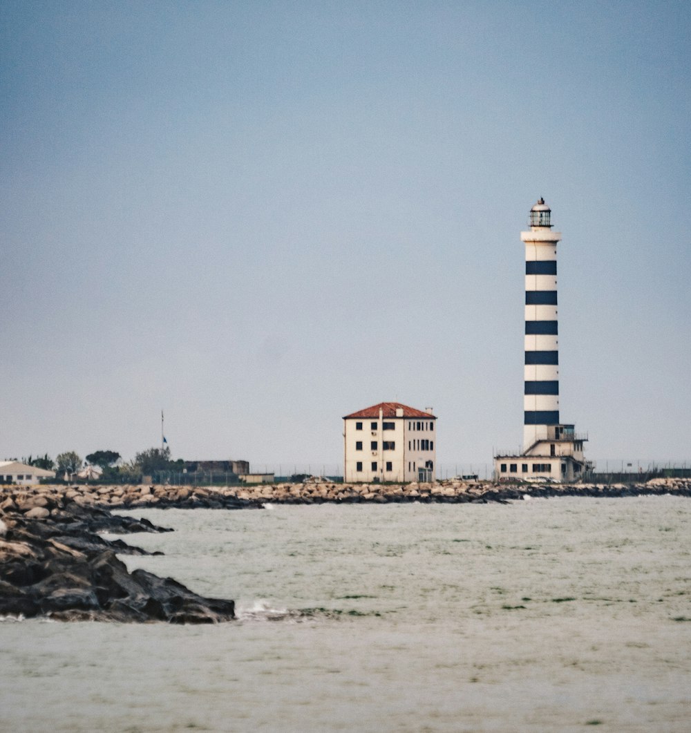 white and blue light house near body of water during daytime