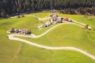 An aerial view of a quaint village nestled in lush green hills.