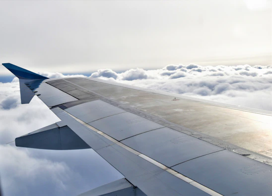 A sleek airplane wing with detailed spare parts laid out on a workbench in a bright, modern workshop.