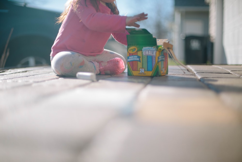 girl sitting beside box of chalk