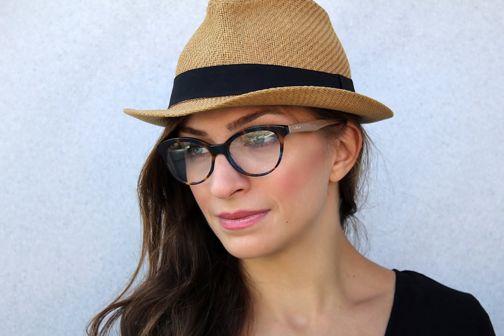 Femme portant des lunettes et un chapeau fedora marron