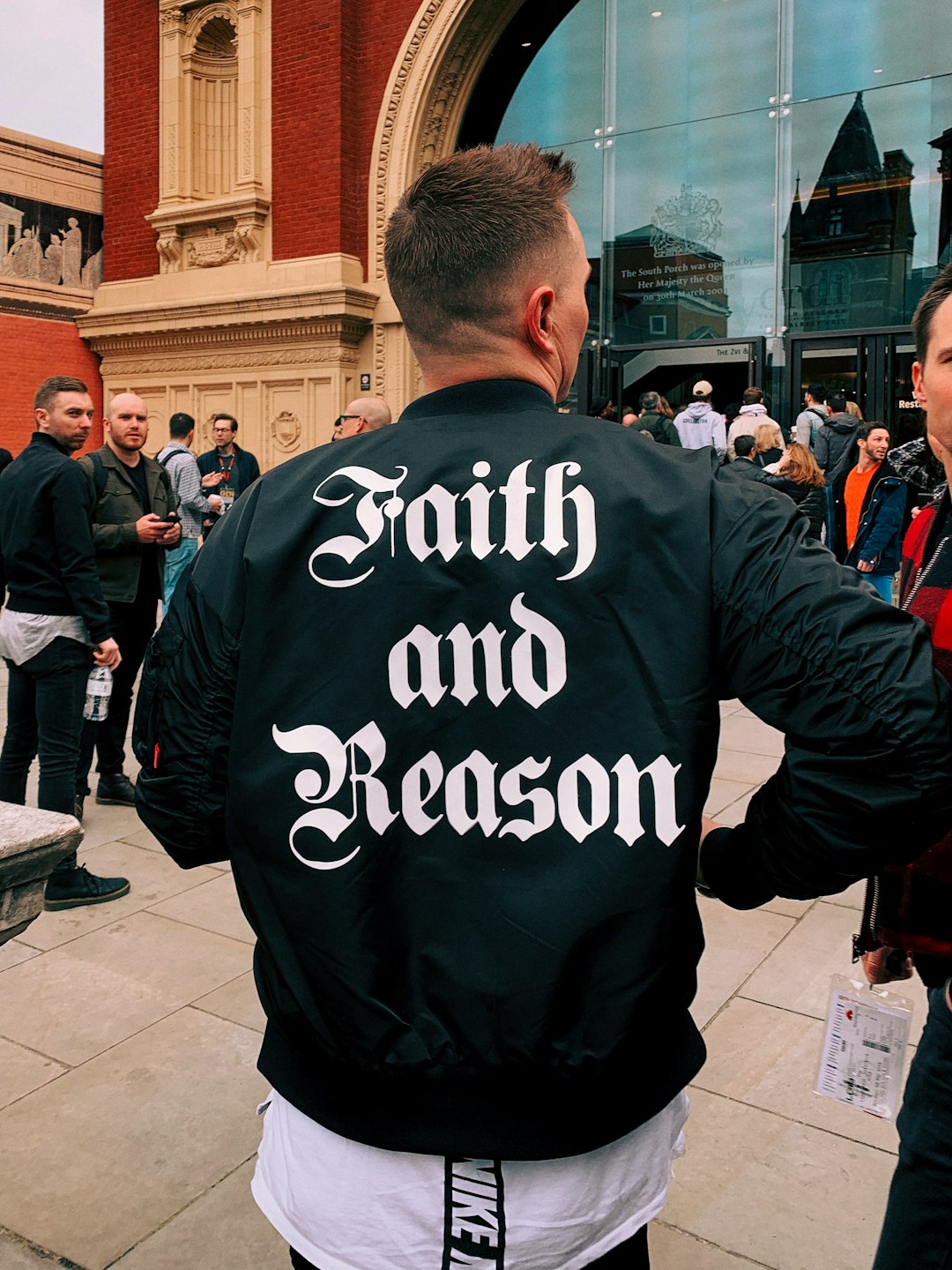 man wearing black leather jacket with faith and reason print on back