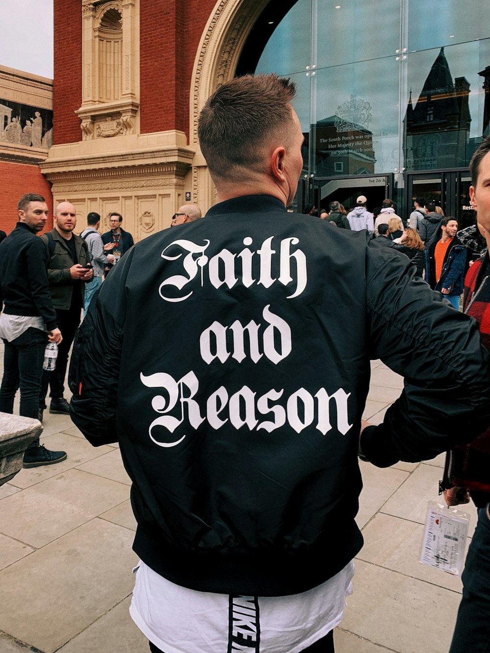man wearing black leather jacket with faith and reason print on back