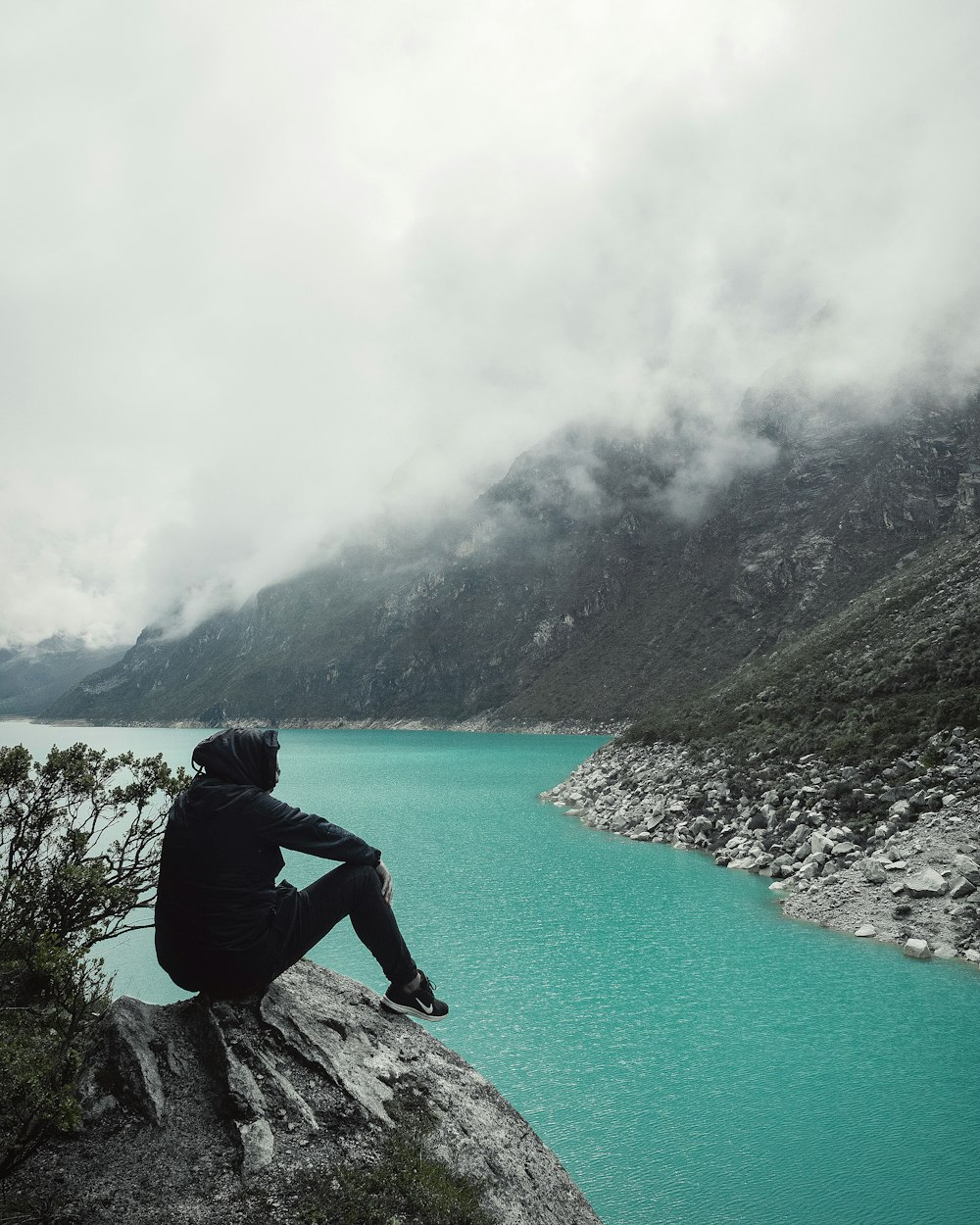 person sitting on cliff with overlooking lake