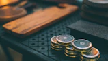 A close-up of hands stacking coins on a wooden table, representing saving and financial growth.