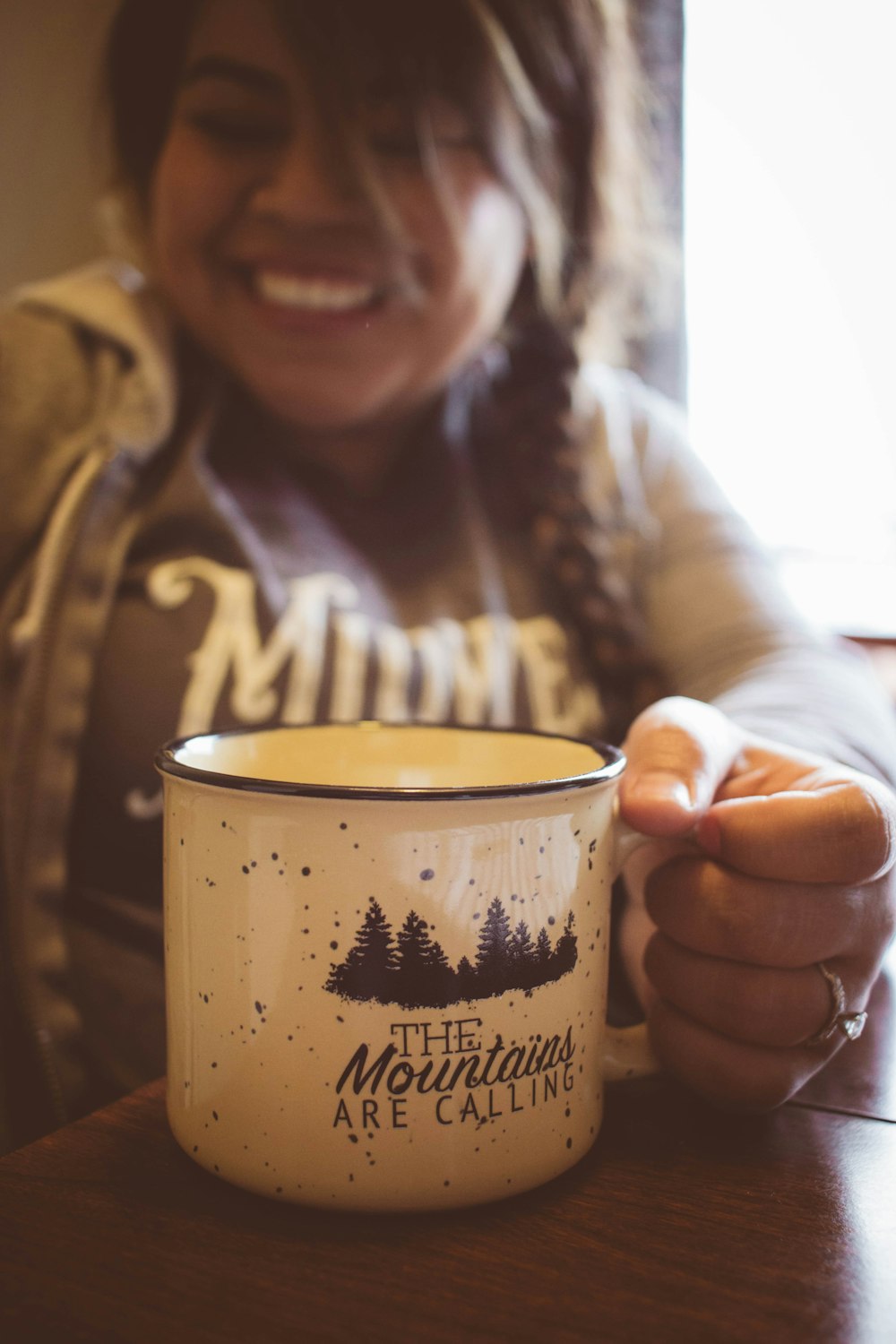 person smiling holding white and black cup