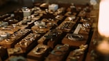 A collection of various pieces of jewelry, including rings, bracelets, and necklaces, displayed on wooden blocks. The arrangement is illuminated with warm lighting, creating a cozy and inviting atmosphere.