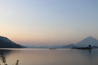 A serene lake reflecting the soft colors of a sunset with mountains in the background.