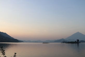 A serene moonlit lake reflecting soft amber and dusty rose hues under a gentle night sky.