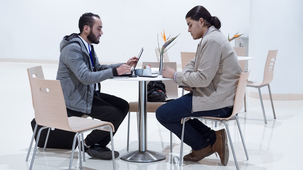 Hombre sentado usando computadora portátil cerca de la mujer sentada al lado de la mesa