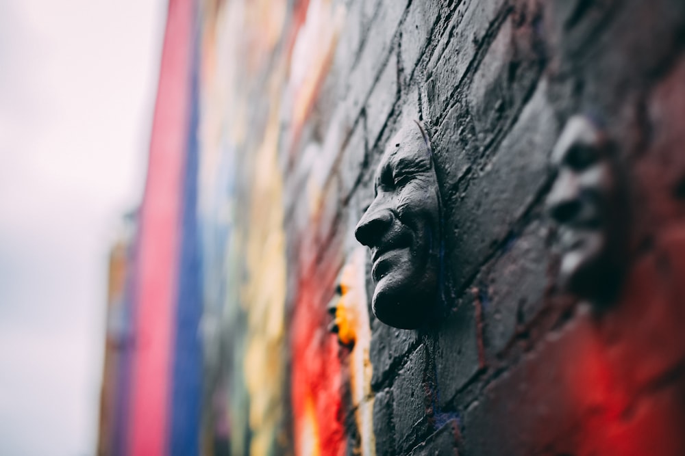human faces embossed on brick wall with mural