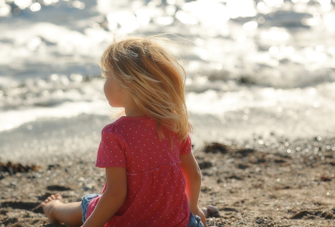girl sitting on seashore during daytime