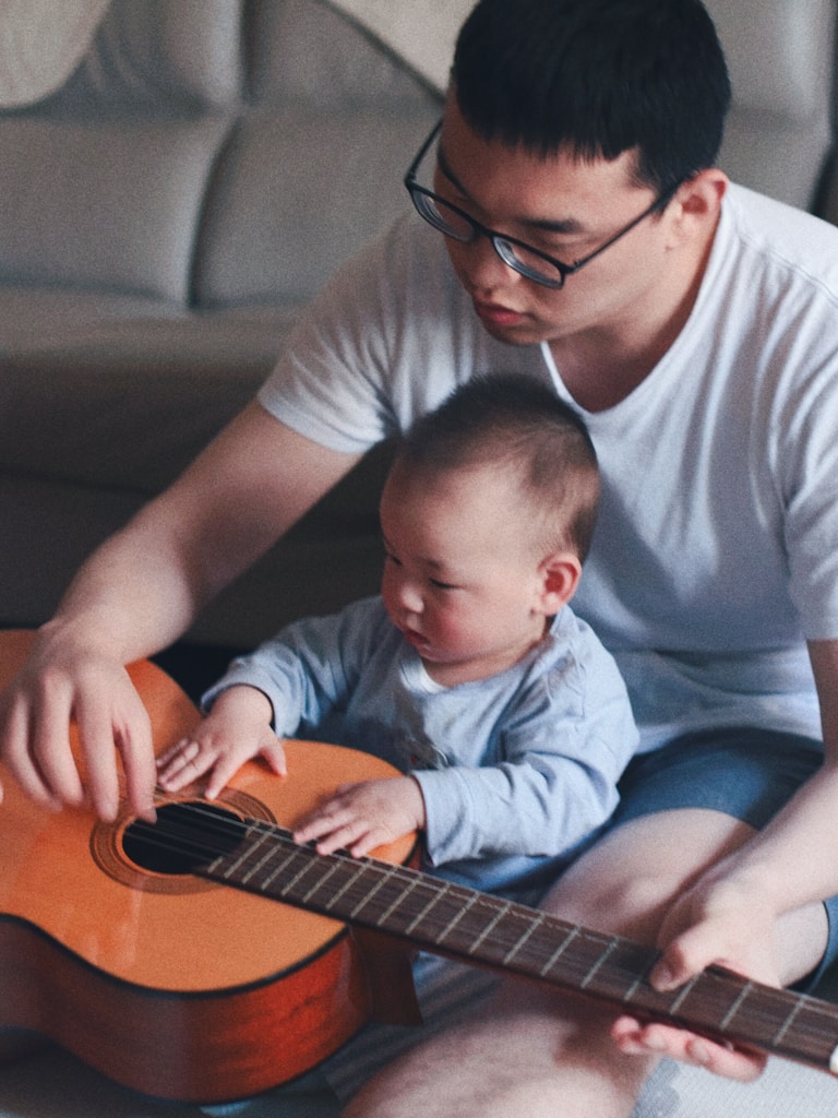 man beside baby holding guitar