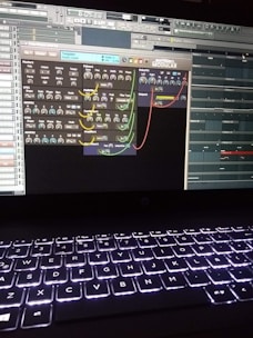 A computer screen displays a digital audio workstation with various audio controls and modules visible. The screen is filled with plugins and mixer settings for music production. Below the screen, a laptop keyboard is visible, illuminated by a backlight.