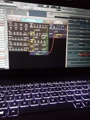 A computer screen displays a digital audio workstation with various audio controls and modules visible. The screen is filled with plugins and mixer settings for music production. Below the screen, a laptop keyboard is visible, illuminated by a backlight.