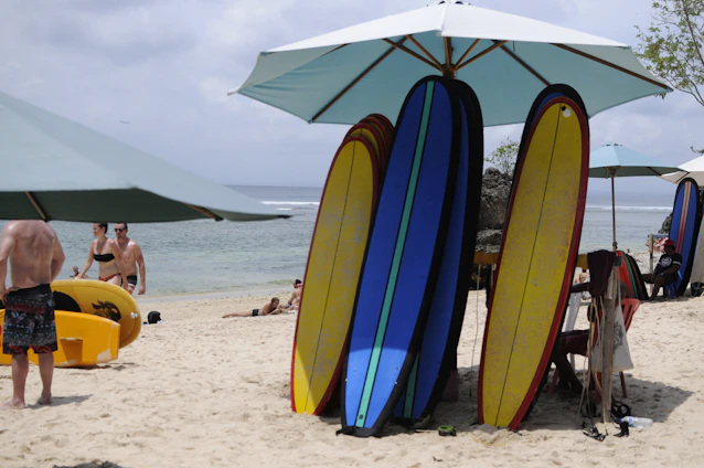 A vibrant beach scene with surfboards resting on the sand under a clear blue sky.