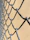 Close-up of a repaired chain-link fence with a technician inspecting the work in a residential area.