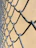 Close-up of a repaired chain-link fence with a technician inspecting the work in a residential area.