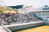 Audience sitting on grass watching an open-air performance.