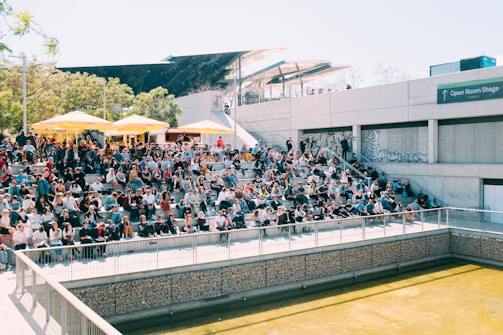 Audience sitting on grass watching an open-air performance.