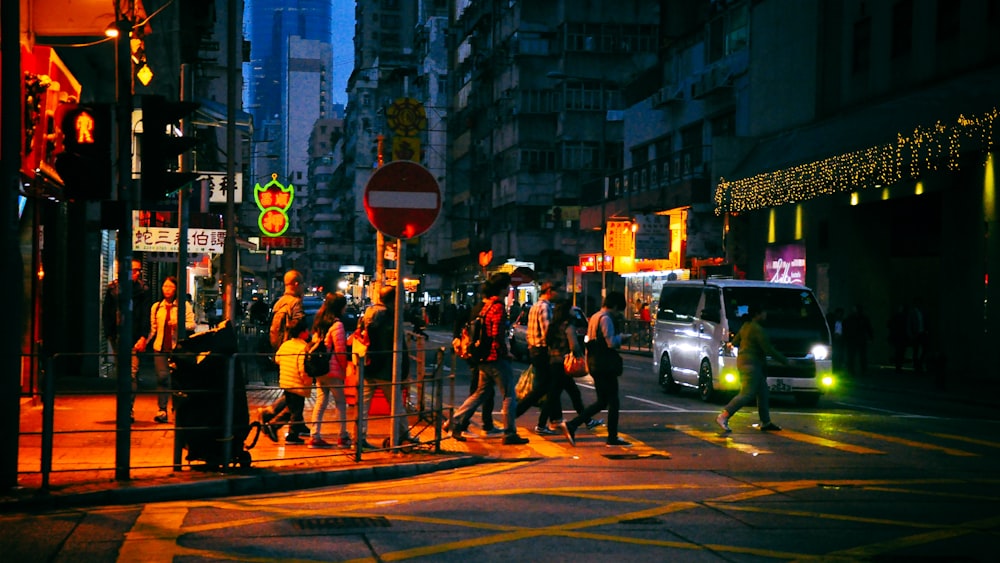 photo of people crossing street during nighttime
