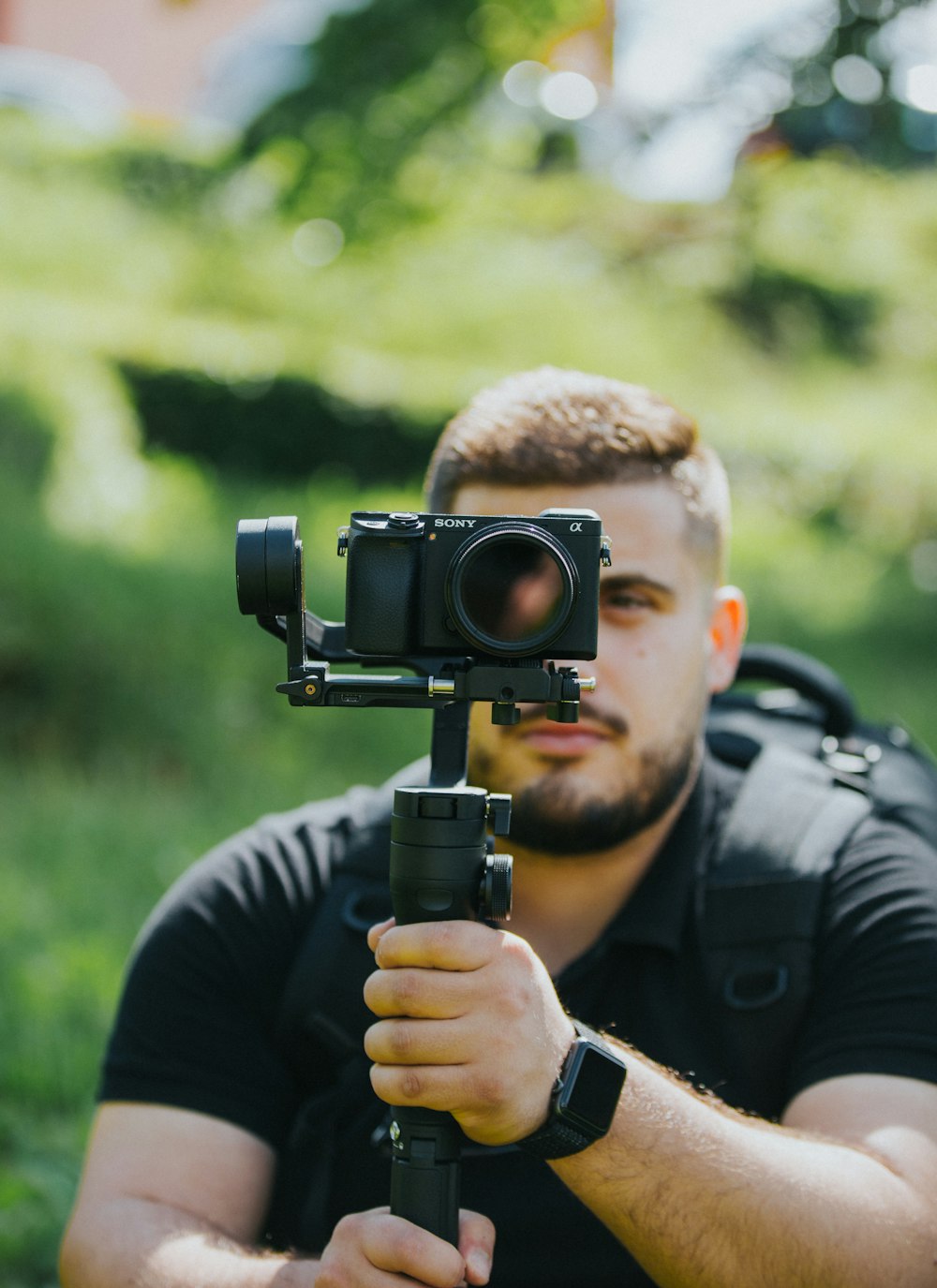 man wearing black shirt holding Sony DSLR camera