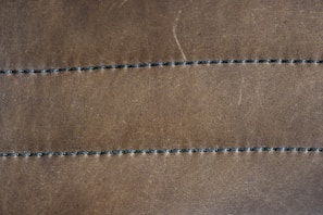 Close-up of a rich brown leather desk pad with elegant stitching on a wooden office desk.