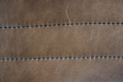 Close-up of artisan hands stitching rich brown leather with precision.