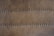 A close-up view of a brown leather surface with two parallel rows of dark stitching running horizontally across it. The texture of the leather is visible, with slight imperfections and a matte finish. The stitching appears uniform and evenly spaced.