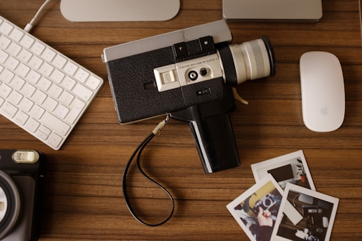 A vintage Super8 film reel next to a USB stick on a wooden table.